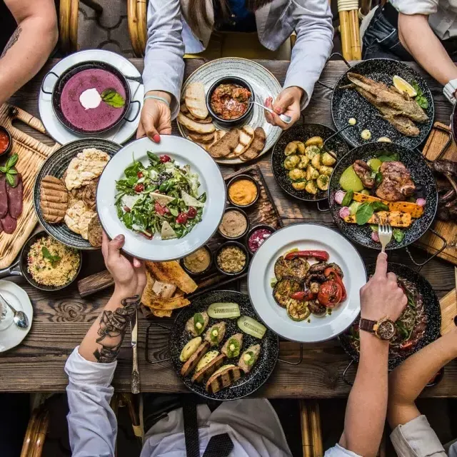 Persone sedute a un tavolo da pranzo che condividono il cibo.